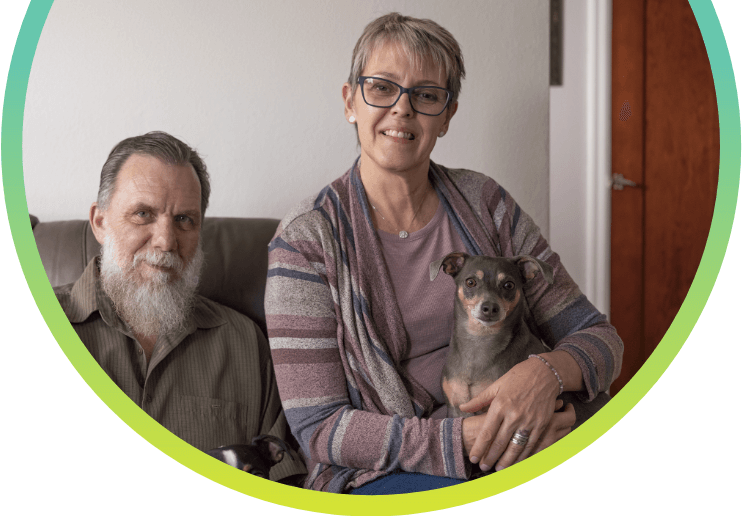A man and a woman sitting together with a dog on her lap.
